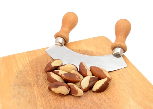 Whole brazil nuts with a rocking knife on a wooden chopping board