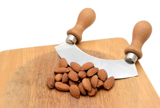 Whole almonds with a rocking knife on a wooden chopping board