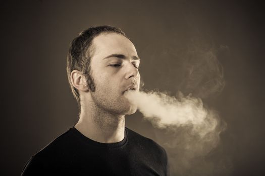 Man exhales smoke on dark background. Closeup