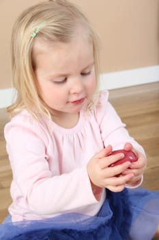 Little girl playing on a wooden floor wearing pink and blue