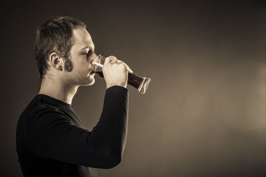 Man drinking beer on dark background. Closeup