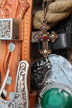Ornate copper jewellery cross on chain against belts