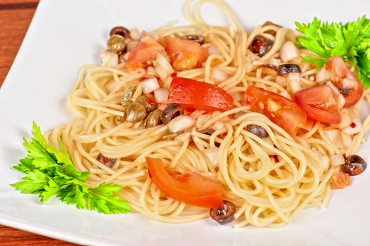 Pasta with tomato, black olives, capers and greens