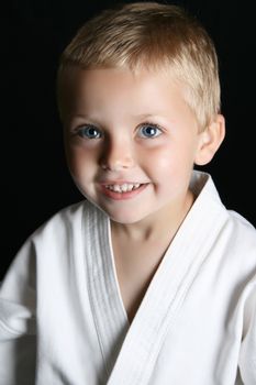Blond boy with blue eyes in karate uniform