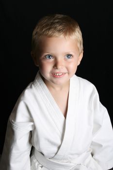 Blond boy with blue eyes in karate uniform
