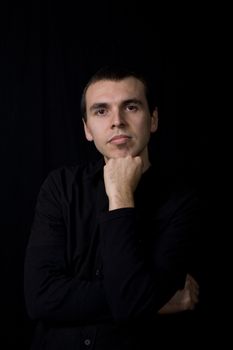 young pensive man portrait, on a black background