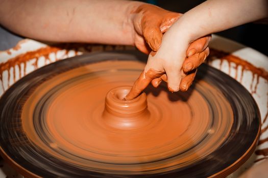 The teacher teaches to sculpt in clay pot on a turning pottery wheel.