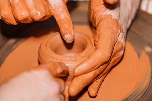 The teacher teaches to sculpt in clay pot on a turning pottery wheel.