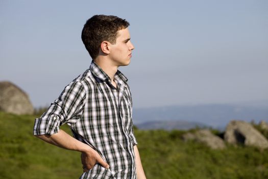 pensive young casual man at the top of the mountain