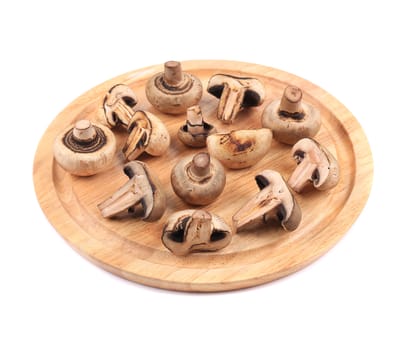 Mushrooms on wooden platter. Isolated on a white background.