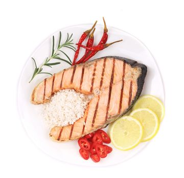 Grilled salmon steak with vegetables on plate. Isolated on a white background.