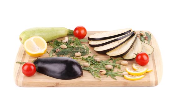 Vegetables with pistachios on wooden platter. Isolated on a white background.
