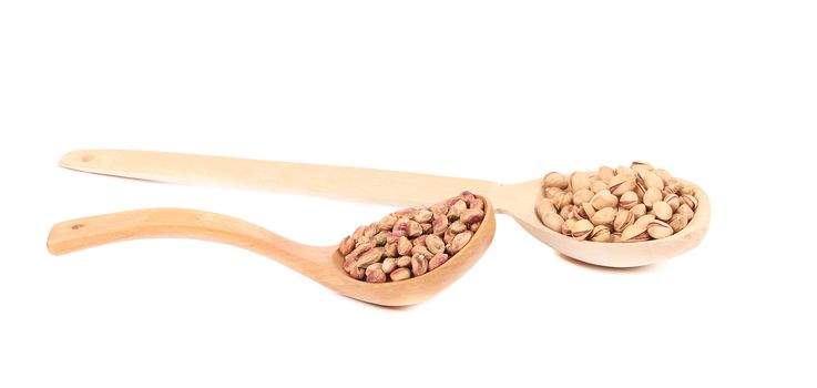 Wooden spoons of pistachios with shell and without. Isolated on a white background.