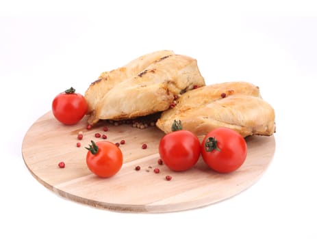 Grilled chicken with tomatoes on wood platter. Isolated on a white background.