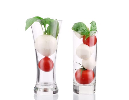 Tomatoes and mozzarella balls in glass. Isolated on a white background.