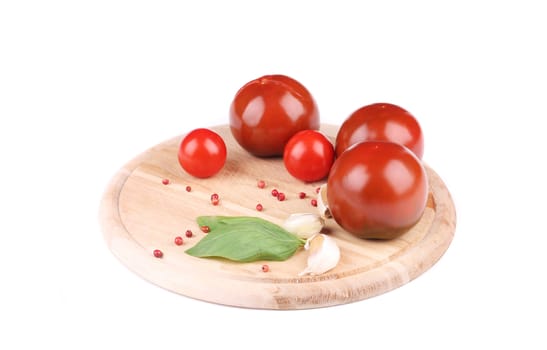 Tomatoes with garlic and basil on platter. Isolated on a white background.