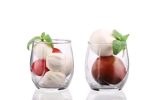 Tomatoes and mozzarella balls in glass. Isolated on a white background.