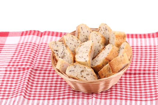 Wicker basket with bread slices on tablecloth. Whole background.