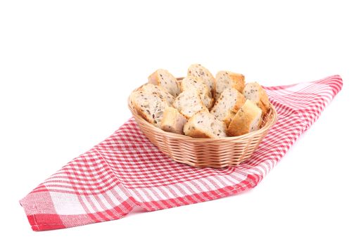 Wicker basket with bread slices on tablecloth. Isolated on a white background.