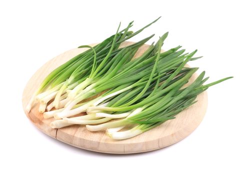 Spring onion on wooden platter. Isolated on a white background.