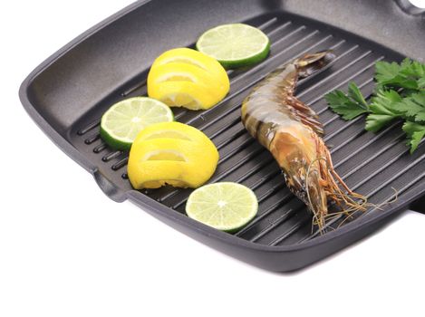 Frying pan with shrimp and lemon slices. Isolated on a white background.