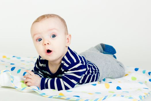 Portrait of a cute baby in striped clothes lying down on a blanket