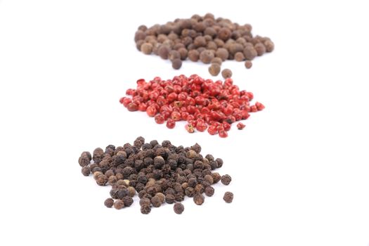 Three spicy peppercorn heaps. Isolated on a white background.