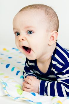 Portrait of a cute baby in striped clothes lying down on a blanket