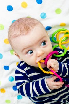 Portrait of a cute baby in striped clothes lying down on a blanket