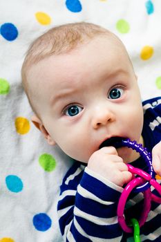 Portrait of a cute baby in striped clothes lying down on a blanket