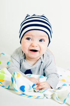 Portrait of a cute baby in striped hat lying down on a blanket