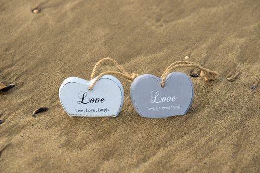 two inscribed wooden love hearts sinking in the quicksand on a wild Atlantic way Irish beach in summer