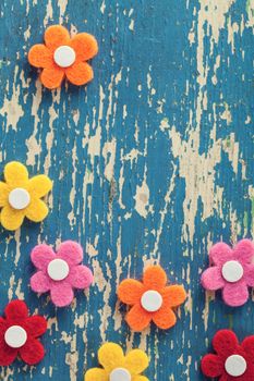 Spring colorful felt flowers on wood background. Top view