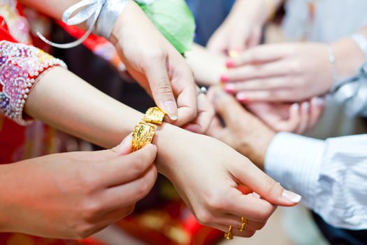 Elderly relatives presenting the golden bracelet as a blessing in chinese wedding