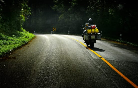 Touring by motorbike on the road with forest beside