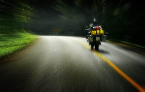 Touring by motorbike on the road with forest beside