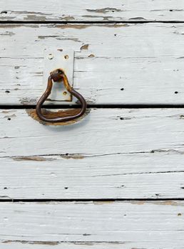 Grunge picture of an old rusty doorknocker on a wooden door, background with copy space.