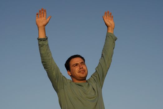 young man with arms wide open at sunset light