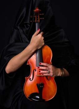Woman draped in black holds her treasured violin musical instrument
