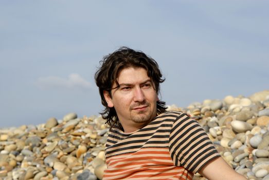 young casual man at the beach stones