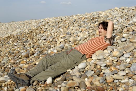 young casual man at the beach stones