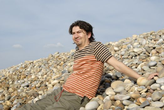 young casual man at the beach stones