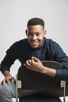 Portrait of handsome dark skinned male model smiling and wearing casual clothes against white background