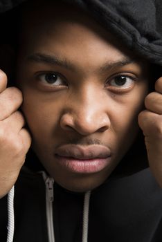 Portrait of handsome dark skinned male model wearing black hooded jumper
