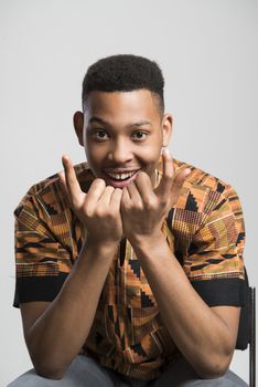 Portrait of handsome dark skinned male model smiling and wearing traditionally African clothes against white background