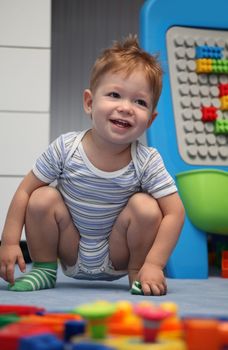 A happy baby boy on a floor in children's room