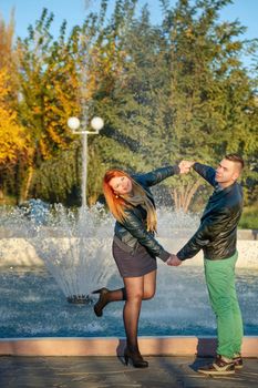 Young heterosexual couple standing at the fountain holding hands spring day