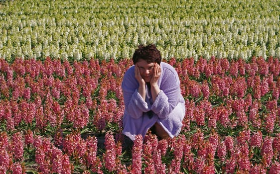 woman in a bathrobe on a field of red and white hyacinths