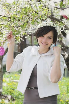 Happy woman with wreath among spring garden