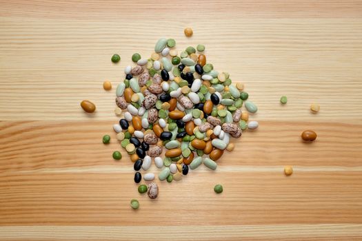 Mixed dried beans - black turtle beans, flageolet beans, pinto beans, brown beans, haricot beans, green split peas and yellow split peas - on a wooden background
